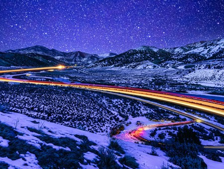 Image of snowy lanscape with car lights lighting up toward the horizon