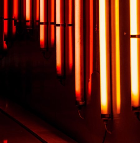 Bright orange vertical neon lights along a body of water