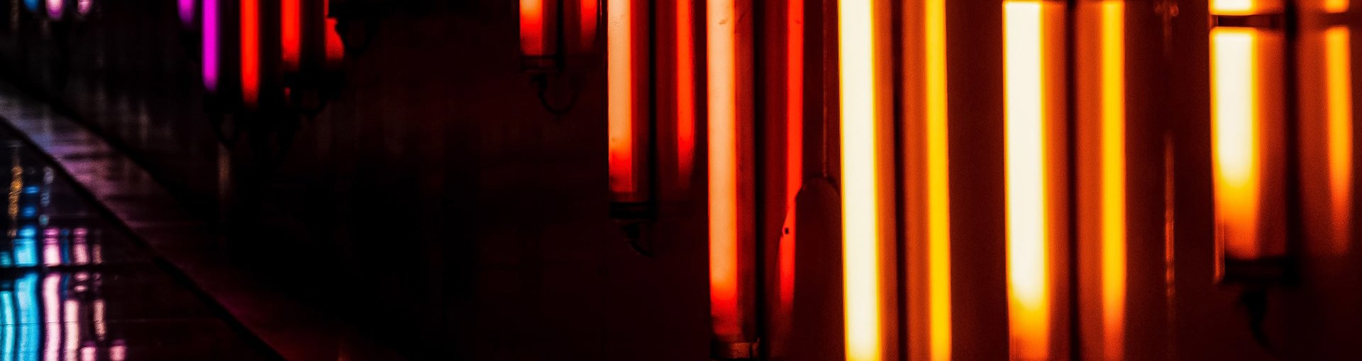 Bright orange vertical neon lights along a body of water