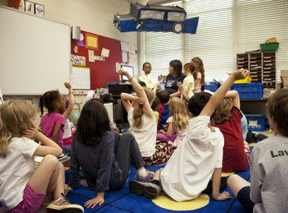 Children in classroom setting with their hands up