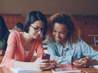 Young people looking at a phone in a classroom setting